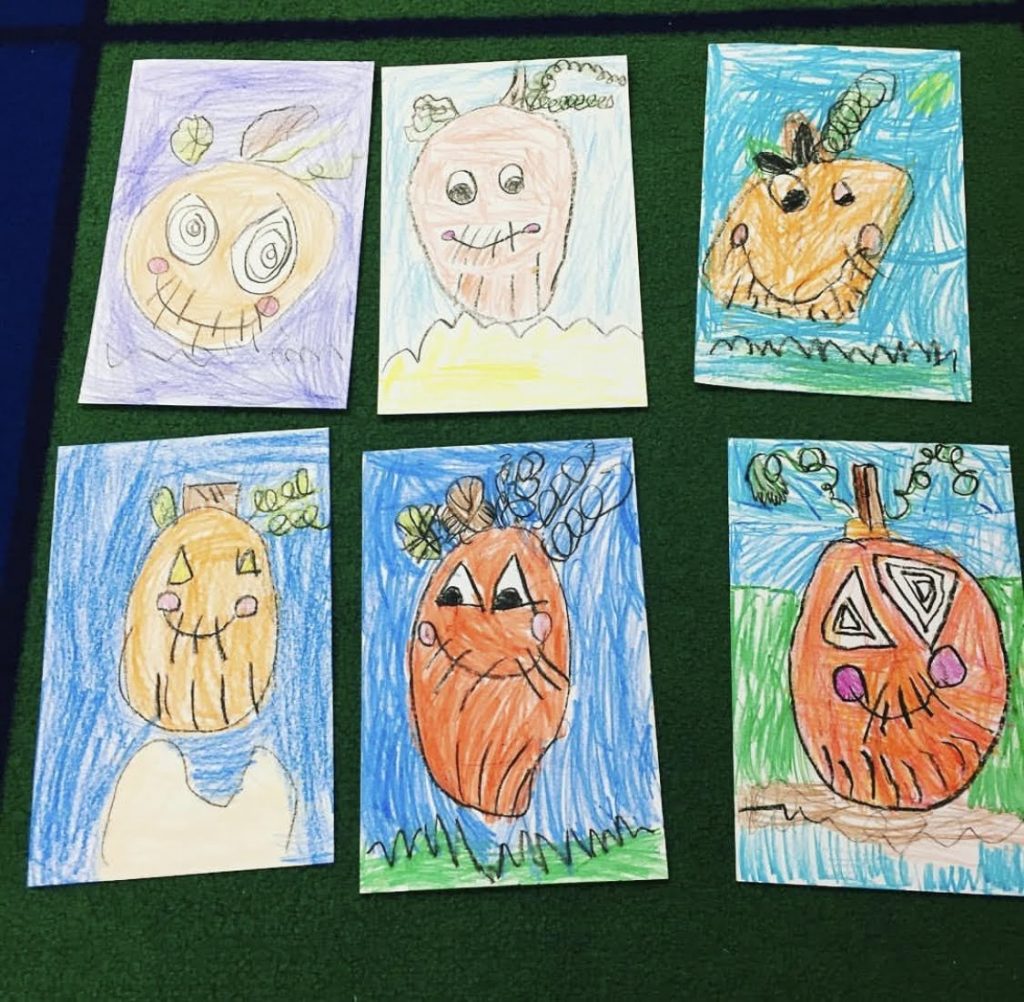 Children's art using a pumpkin directed drawing worksheet.